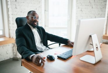 Calling, talking on phone. African-american entrepreneur, businessman working concentrated in office. Looks serios, busy, wearing classic suit. Concept of work, finance, business, success, leadership.