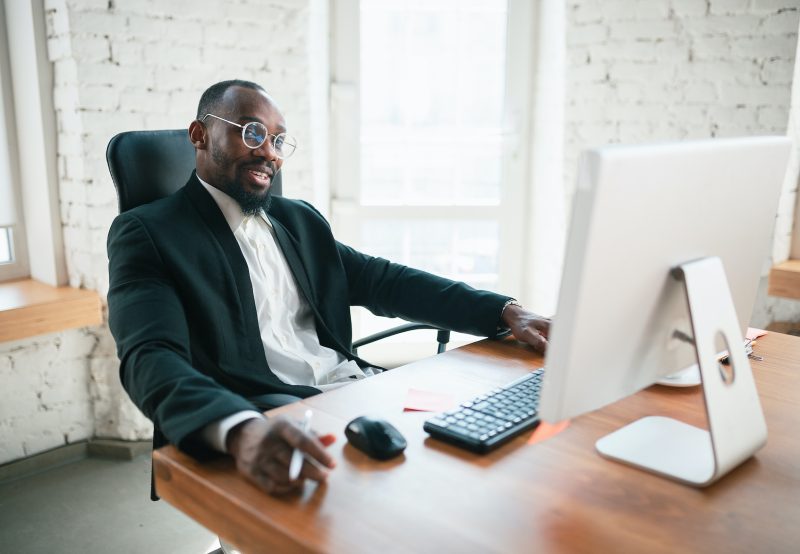 Calling, talking on phone. African-american entrepreneur, businessman working concentrated in office. Looks serios, busy, wearing classic suit. Concept of work, finance, business, success, leadership.